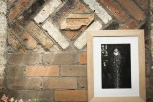 Black and white print of light house framed in thick oak on a brick wall