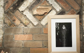 Black and white print of light house framed in thick oak on a brick wall