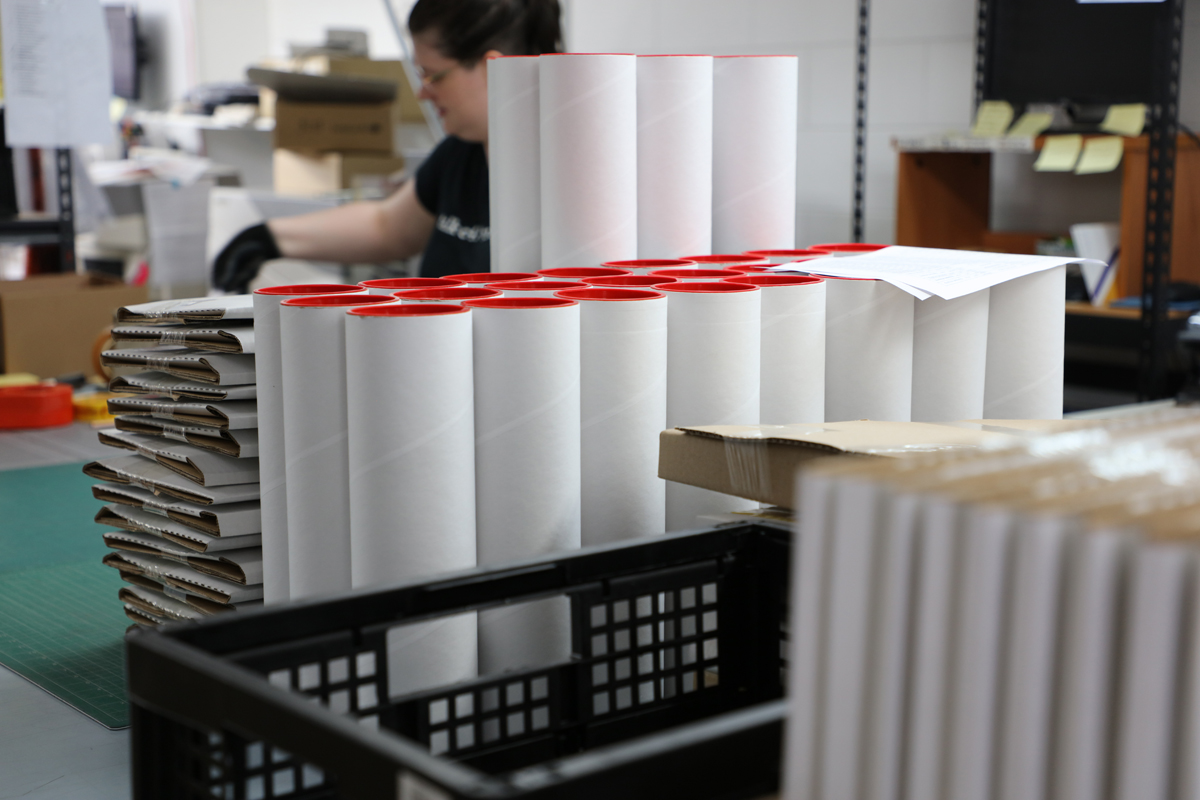 Workspace full of packages and carboard tubes ready to send