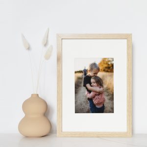 Oak framed print of brother and sister on lustre photo paper leaning against white wall