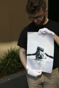 Lab Staff holding a black and white print of a woman on a surfboard printed on kodak professional endura metallic