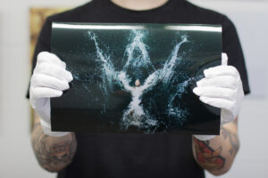 Lab staff holding and image of a man in the sea printed on Kodak professional gloss metallic paper