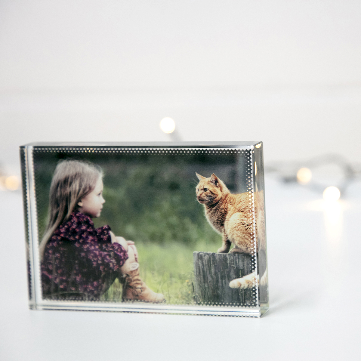 Glass photo block with image of girl and orange cat backlit by fairy lights