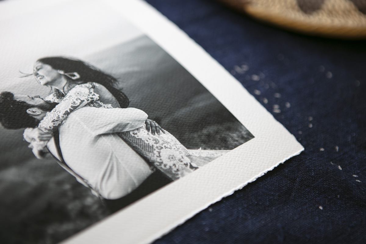 Close up of the corner of a textured aquarelle rag photo print with a white border and torn edge of a bride and groom in black and white