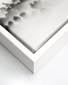 Close up of the corner of a black and white image printed on canvas with a white float frame