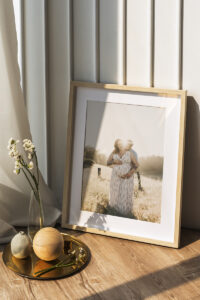 Oak framed print of a pregnant woman being hugged by father sitting on a wooden table