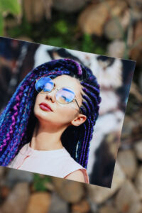 Glossy photographic print of a woman wearing glasses with colourful dreds