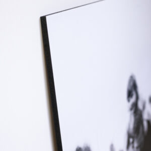 Corner of a black and white photo printed and mounted onto a 12mm block mount with black edge leaning against a white wall