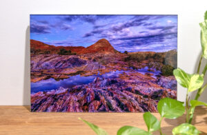 Acrylic flush mount print of a mountain with vibrant colours on a wooden table with plants