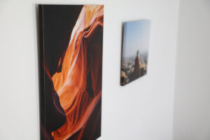 Pearl wrap photo of a cave next to a lustre wrap photo of a woman at a look out hanging on a white wall