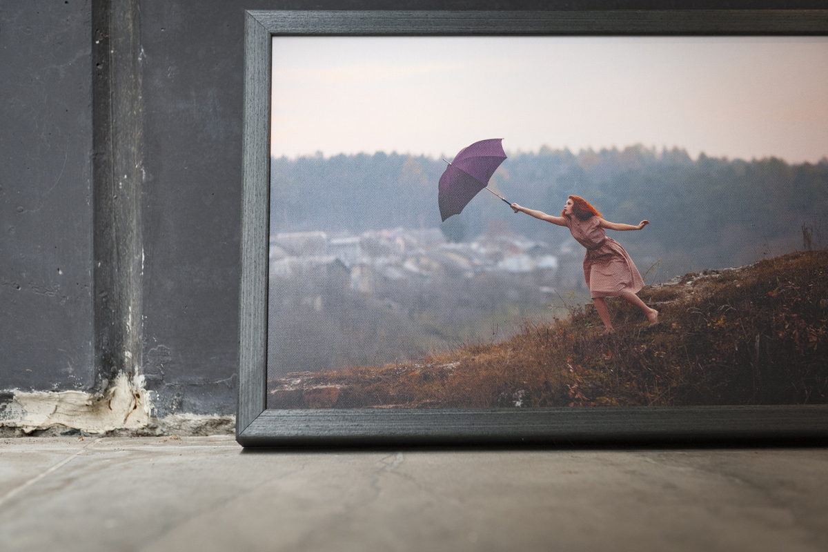 Grungy charcoal framed print of a red haired woman holding an umbrella on the side of a hill