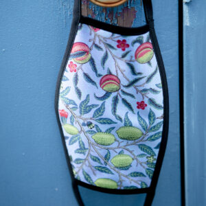 Custom printed face mask hanging from a door knob with a botanical design printed on the face