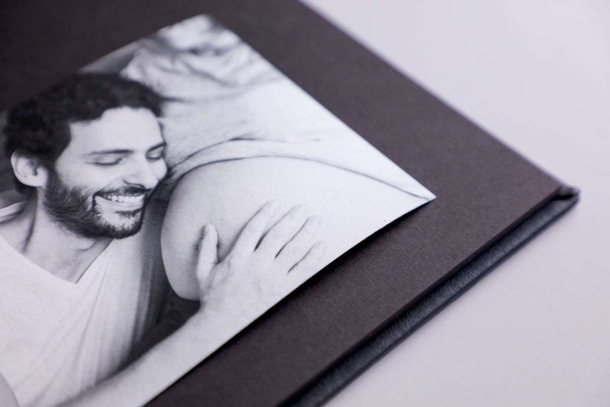 Close up of a dry mount album with a black and white agave print of man holding pregnant belly