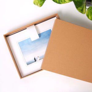 Open craft box on table with matted prints displayed inside