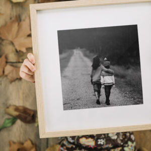 Young person holding an oak framed black and white photograph of two children