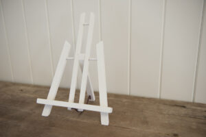 White desktop easel with nothing on it on a wooden bench