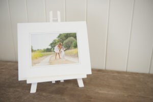 A white matted print of a girl and boy sitting on a white easel