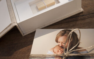 Pile of prints wrapped in twine next to a linen photo box with a spot for a USB stick at the base