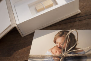 Pile of prints wrapped in twine next to a linen photo box with a spot for a USB stick at the base