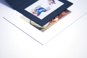 Whiite matted photo print with a photo of a girl in a black photo folder sitting on top