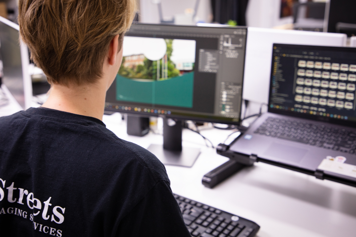 Lab staff sitting at computer designing a template for a school print product