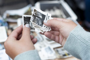 young hands holding very old black and white images with white borders and deckled edges