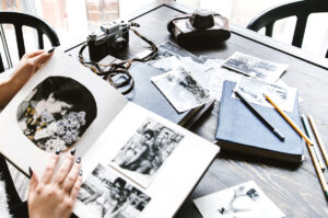 Table covered in old black and white photos and albums along with old cameras