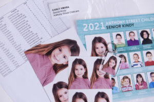 Pile of prints, photo keyring and printed spreadsheet ready for sorting school photos into packs